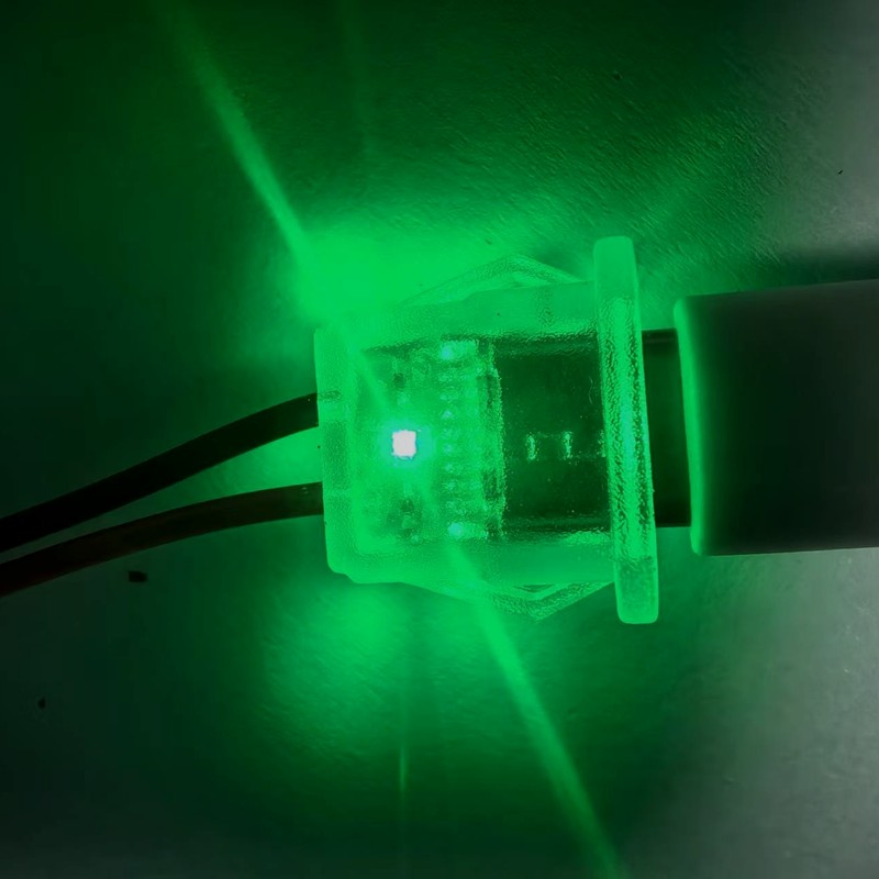 Sample small LED indicator module with red and black pigtail leads, shown illuminated — reference sample